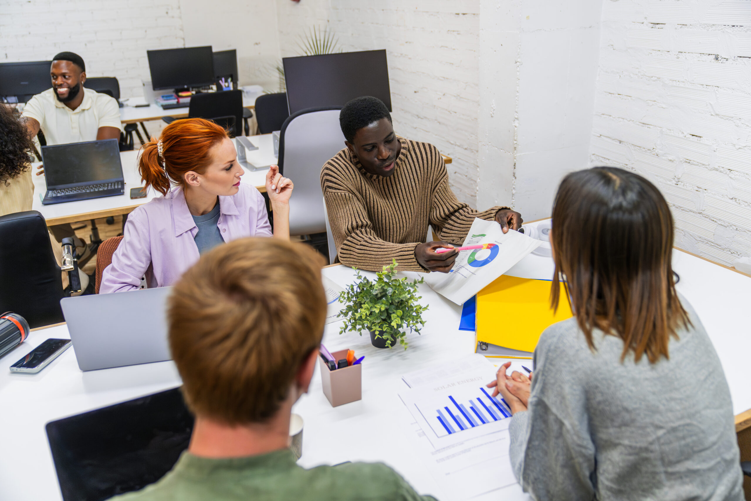 Diverse team of marketing professionals analyzing data and discussing growth strategies during a productive meeting in a modern coworking space