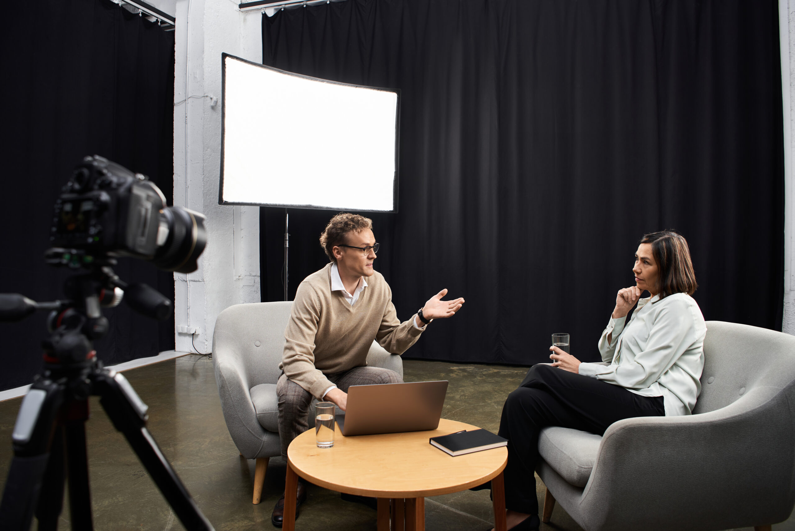 A knowledgeable journalist conducts a professional interview with a specialist in a modern studio environment.
